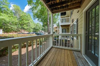 Wood-floored patio with a white railing on the first floor.